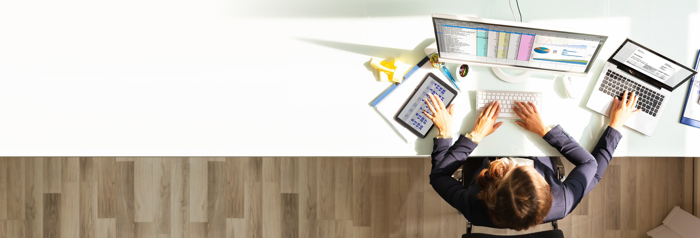 Employee Working on a Tablet, Computer, and Laptop 